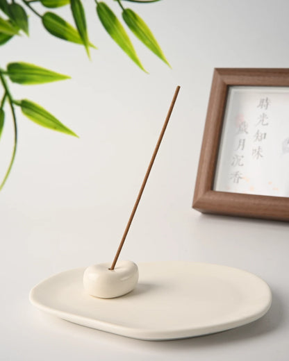 Close view of the glazed stone holder sitting on the unglazed ceramic tray with an incense stick upright