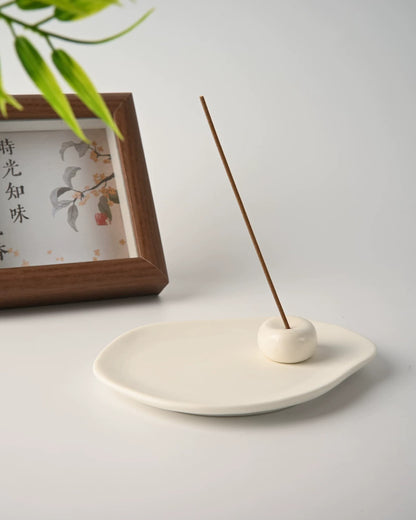 Ceramic incense tray with the stone holder set near one edge and a tall incense stick burning