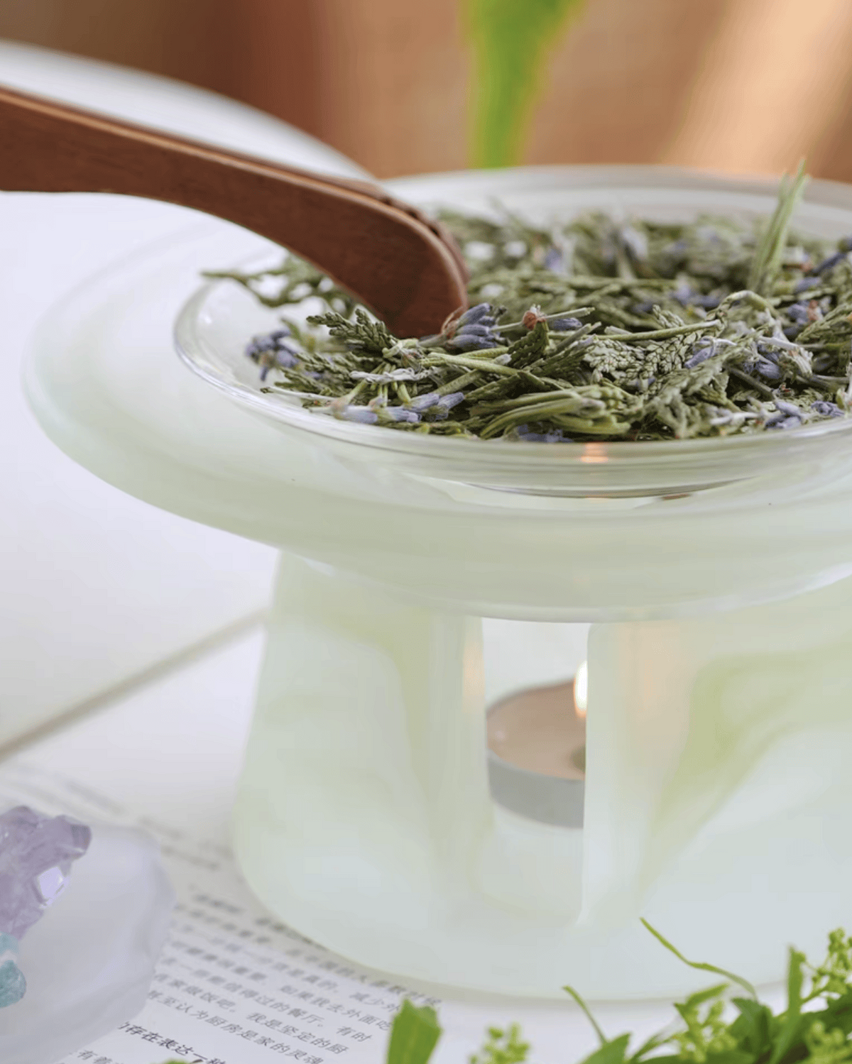 Celadon green glass incense warmer filled with dried lavender, tealight burning in the base below