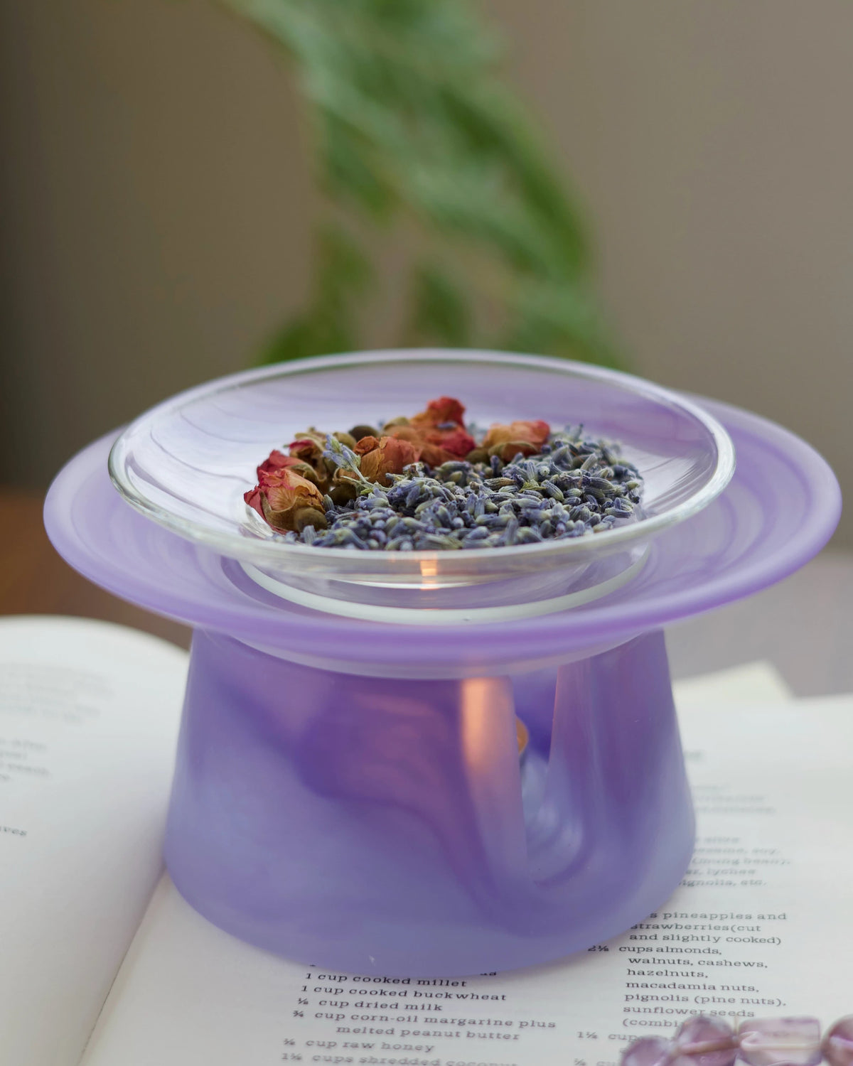 Twilight purple liuli glass incense warmer holding dried rosebuds and lavender buds over a lit tealight